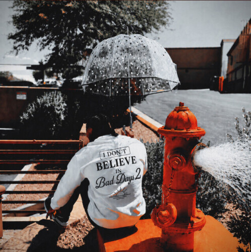 J French album artwork showing a seated figure in a white jacket beneath a clear umbrella beside a red fire hydrant.